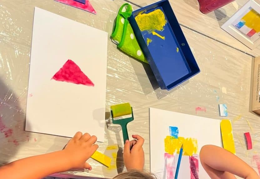 Manos infantiles extendiendo tinta en un taller
